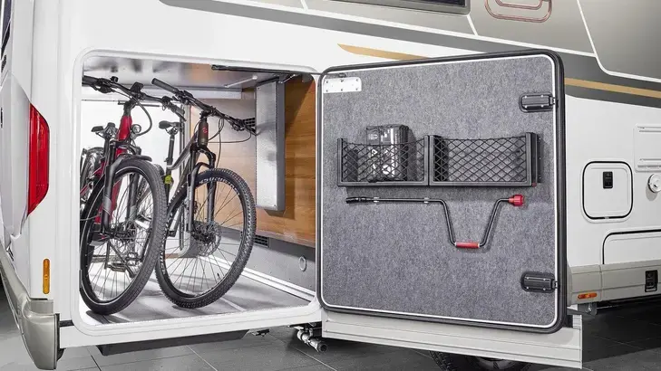 Geöffnete Heckgarage eines Wohnmobils mit Fahrrädern und großem Stauraum.