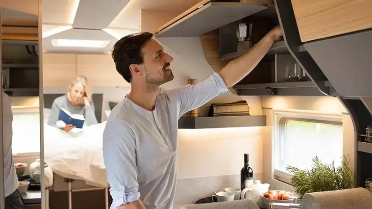 Geöffnete Schränke im Wohnmobil mit Ablagefächern für Geschirr und Zubehör.